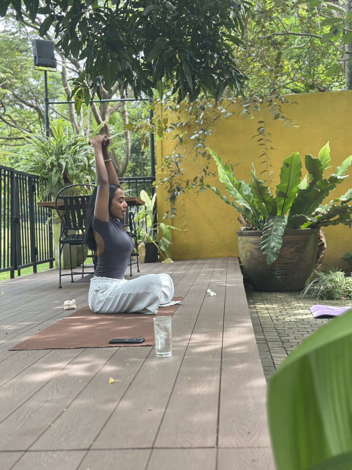 A woman practising yoga with her arms raised on the outdoor deck at Svastha Studio in Kotte