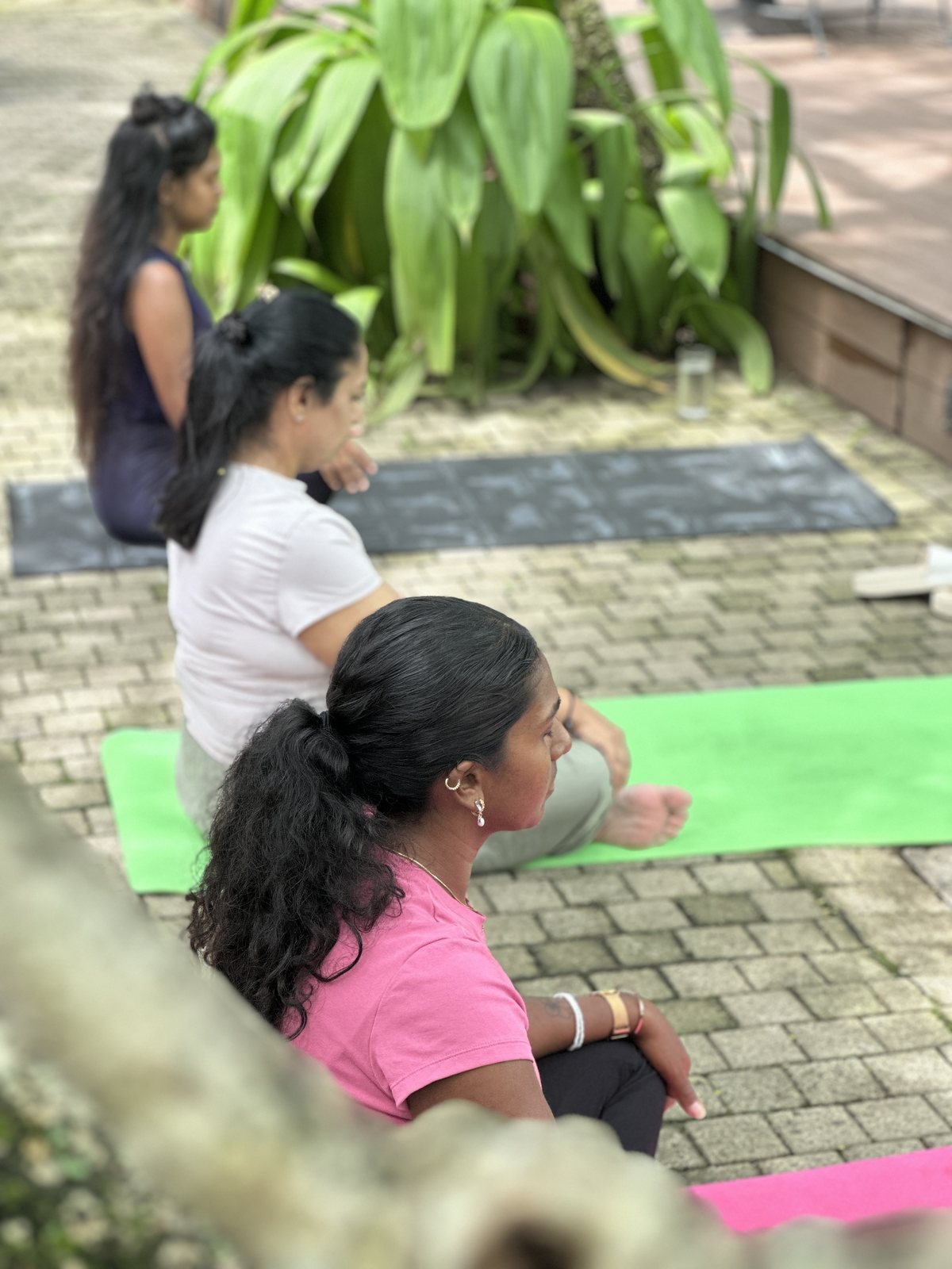 A small group seated on mats for an outdoor yoga class at Svastha Studio in Kotte